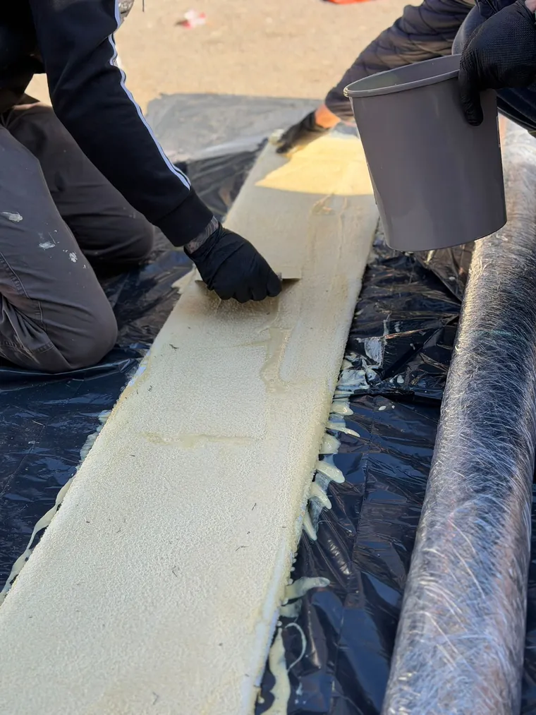 Dva radnika impregniraju CIPP liner smolom na foliji prije ugradnje u cijev